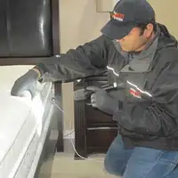 Bed bug inspection technician checking a mattress and bed frame for signs of infestation in Louisville, KY