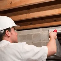 Termite inspection technician checking a basement wall and framing for termite activity in Louisville, KY