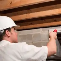 Termite inspection technician checking a basement wall and framing for termite activity in Louisville, KY